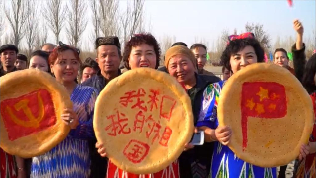 新疆のトルファンで行われた春の祝祭で撮影されたウイグル族のナンの写真 - ハンマーと鎌の中国共産党のロゴ、「私と私の国」を意味するスローガン、中国の国旗（左か右の順番）があしらわれている。