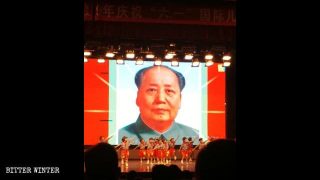 毛沢東の肖像画が掲げられた舞台で「紅い」公演を行う子どもたち。