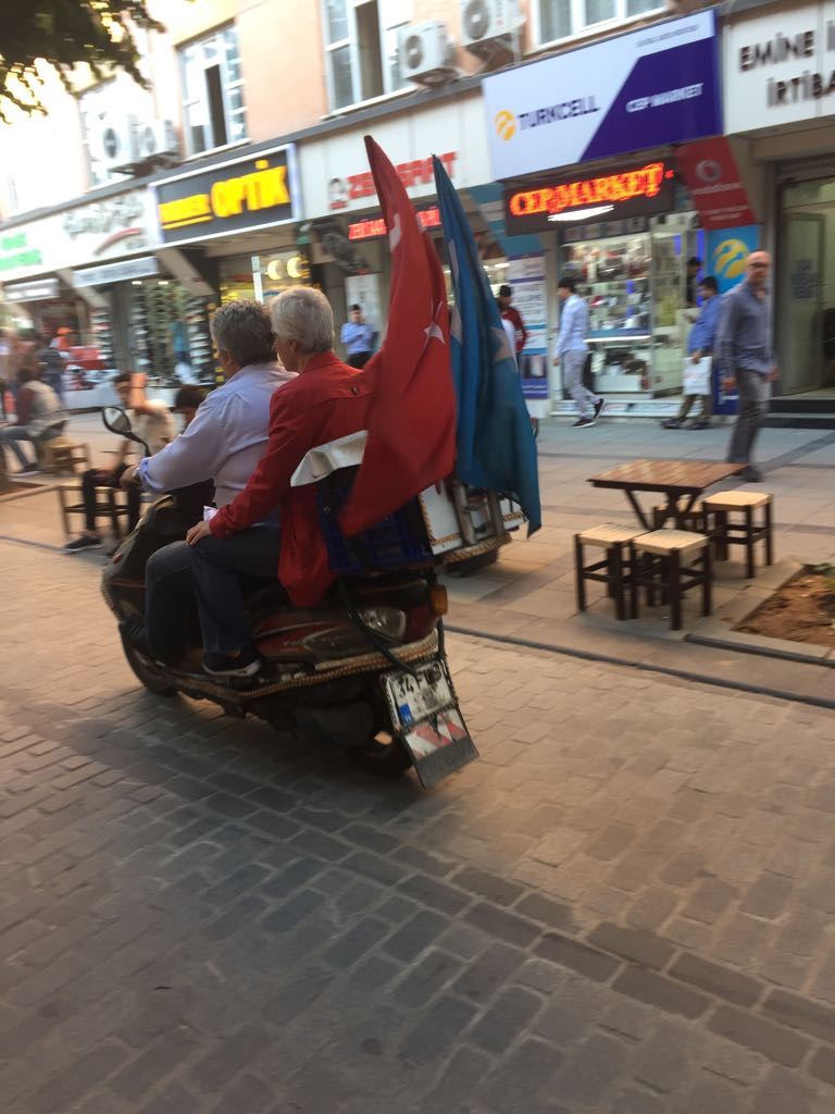 バイクの後ろにトルコとトルキスタンの国旗をなびかせるウイグル族のライダー。