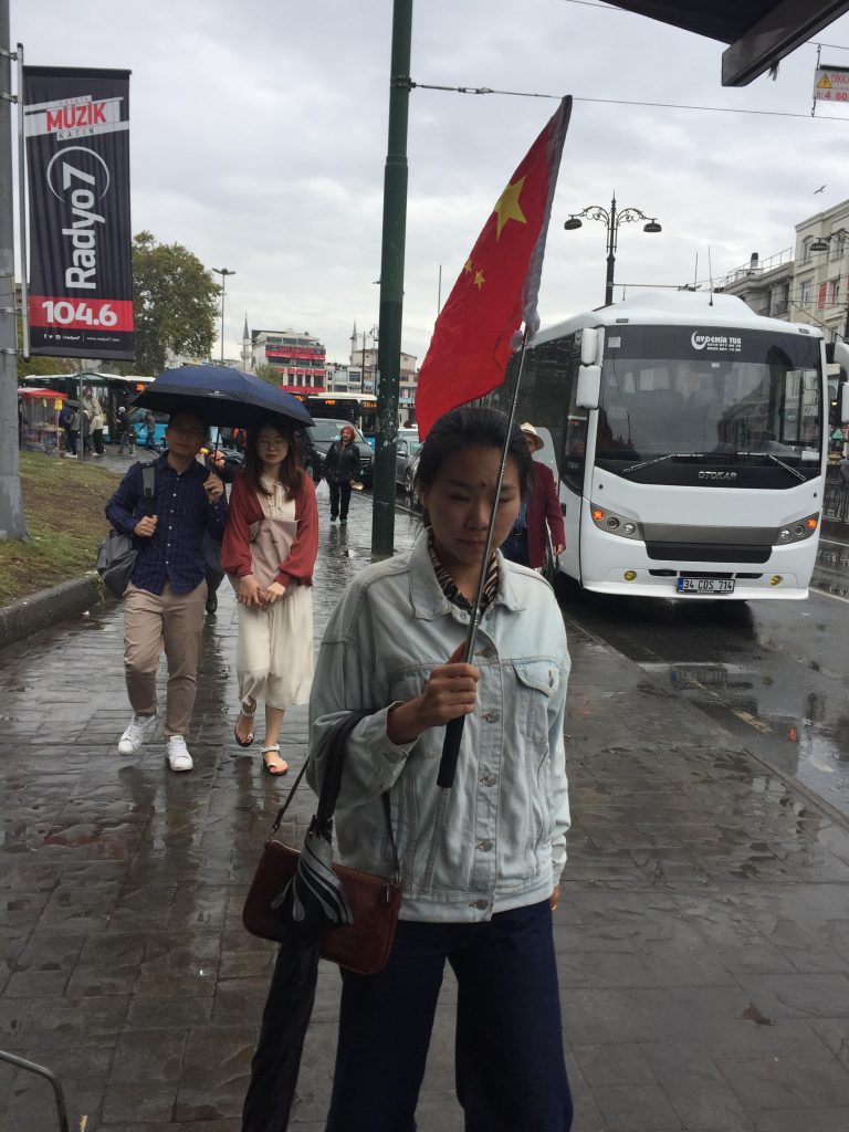 イスタンブールの通りで高く掲げられる中国の紅旗。ツアーガイドが訪問者を古代のバザールに案内している。