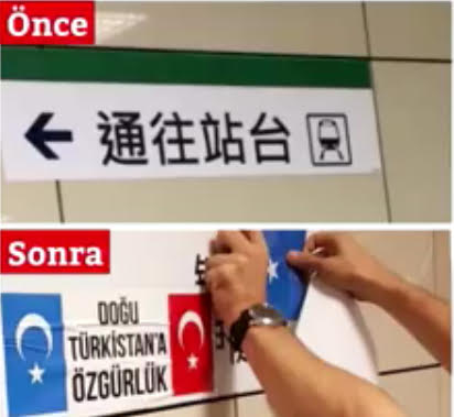 ウイグル族の共鳴者のあるトルコ人が、路面電車のプラットフォームを示す中国語の案内板の下に東トルキスタンとトルコの国旗を貼っている。