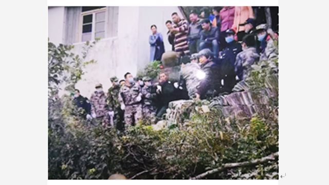 中国共産党の警察が、寺を見張っていた高齢の村民の両手を拘束し、山の麓まで連行する様子