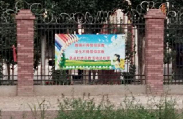 塀に貼られたスローガン：「教師は信仰を持ってはならない。生徒は信仰を持ってはならない」「学校敷地内から宗教活動を完全に根絶しよう」