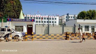 「教育による改心」のための強制収容所に姿を変えたチャプチャル・シベ自治県の第三中等学校の正面入口では武装警官が警備に当たる