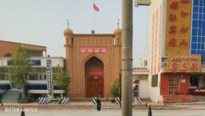 疎勒県ナキウケ通りにあるモスクの周囲をパトロールする警官。中国の国旗がモスクの屋根に掲げられている。