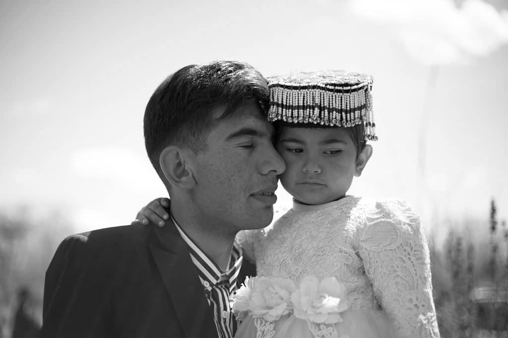 家族の祝い事のために着飾った娘を優しく抱き上げる男性。© マキシム・クローゼー