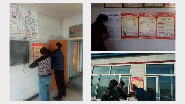 村の委員会事務所の壁に反宗教的なポスターを貼っている政府職員。