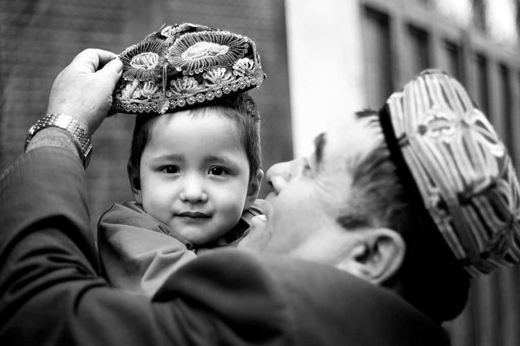 刺繍を施したドッパ（伝統的な帽子）を息子にかぶせる男性。© マキシム・クローゼー
