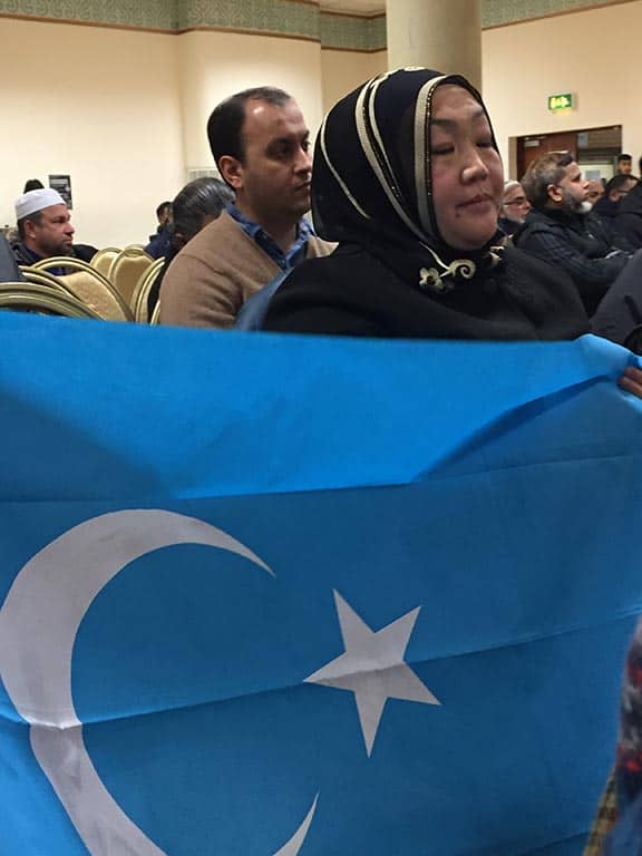 イギリス在住のウイグル人のムスリム。亡命したウイグル人にとって失った故国を象徴する東トルキスタンの旗を広げている。