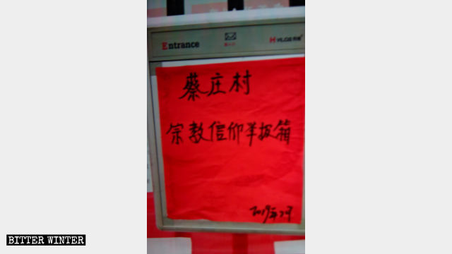 蔡庄村委員会の事務所の壁に掛けられた箱。「宗教信仰通報箱」と書かれている。