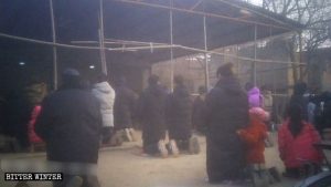謝荘村の屋外ミサの開催中に跪く信者ら。