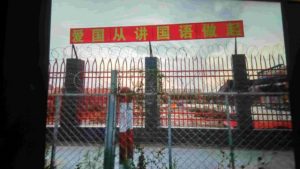 幼稚園の周囲の壁には有刺鉄線が張り巡らされている。壁に掲げられているのは「愛国心は中国語を話すことから始まる」というスローガンだ。