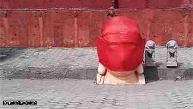 取り壊された仏像の頭が、赤い布で包まれている。