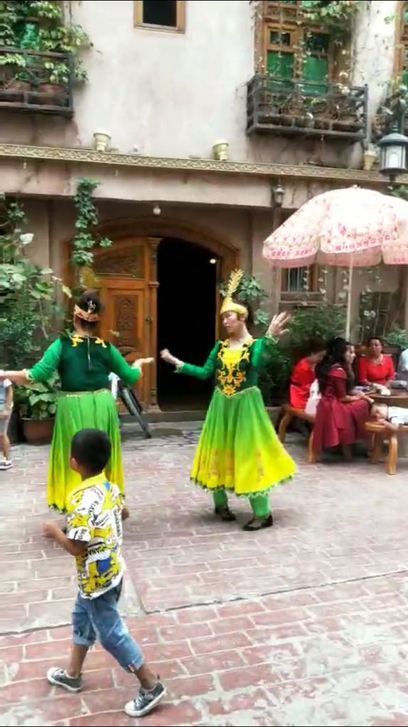 カシュガル市で漢族の旅行客のために踊らされる不機嫌なウイグル族の少女たち。