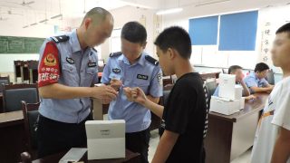 四川省什邡市の公安局所属の警察官が中学生のDNAサンプルを採取している。